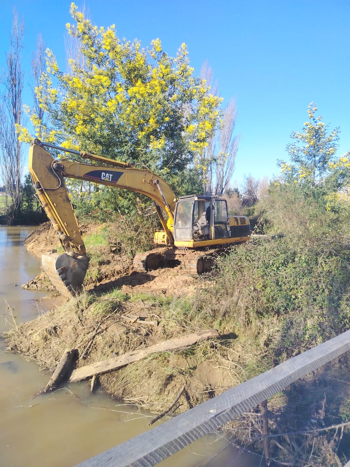 Excavadora hidráulica realizando limpieza y perfilado de un estero